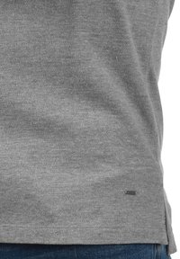 Grå, struktureret sweater med rund halsudskæring. Har en sideslids og et lille logo mærke i kanten. Sammen med blå denim.