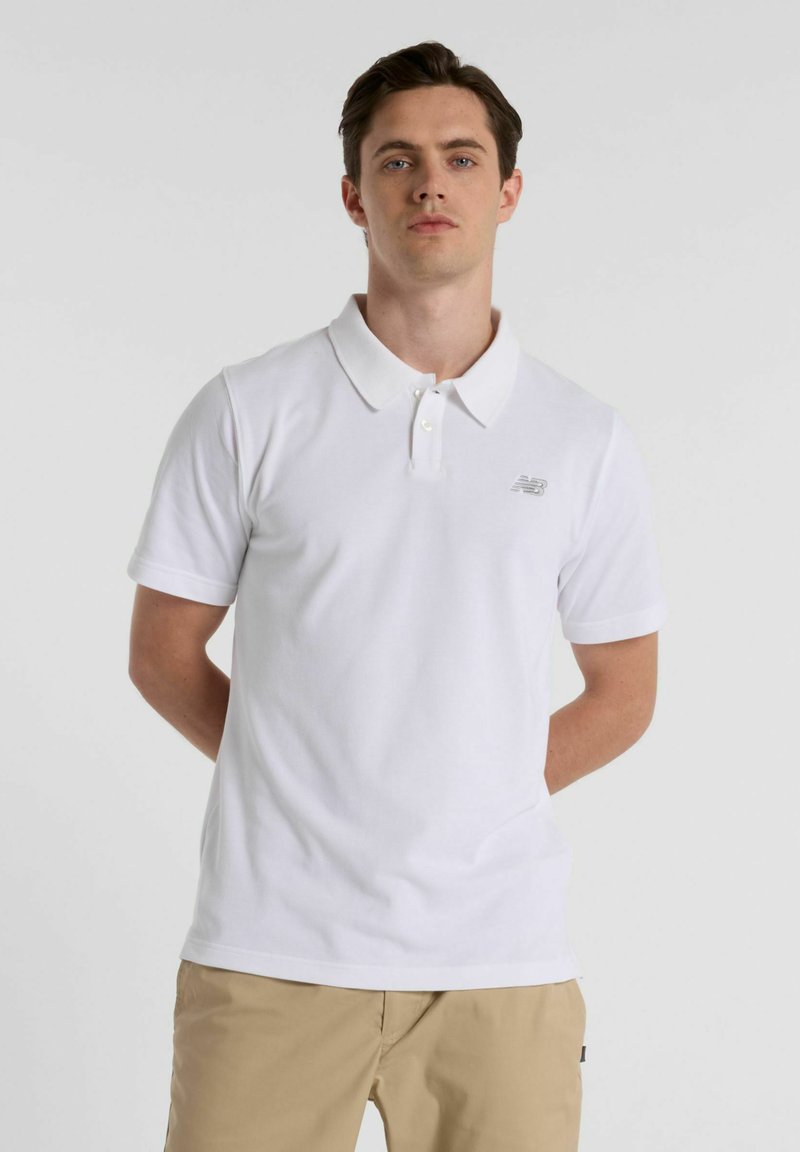 Polo de manga curta branco feito de algodão, com um colarinho clássico e um pequeno logótipo cinza no peito esquerdo.