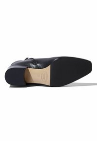 Zapato de cuero negro con punta afilada, diseño elegante, textura suave y tacón cuadrado. La suela es plana con un detalle mínimo.