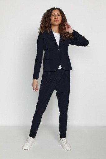 Navy blue blazer with structured shoulders and lapels, paired with matching tapered jogger pants. White t-shirt underneath. White sneakers.