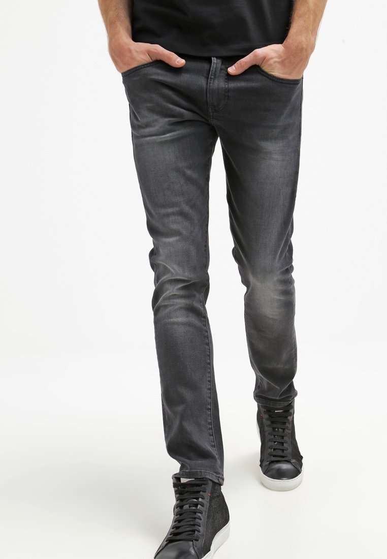 Slim-fit grå denimjeans med en lätt tvätt, fem fickor, bälteöglor och en mjuk textur, kombinerat med svarta högtopps-sneakers.