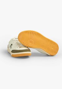 Cremfarbene und olivgrüne Wildledersneaker mit gelben Gummisohlen, die ein Skull-Logo, ein Schnürdesign und strukturierte Muster auf der Laufsohle aufweisen.