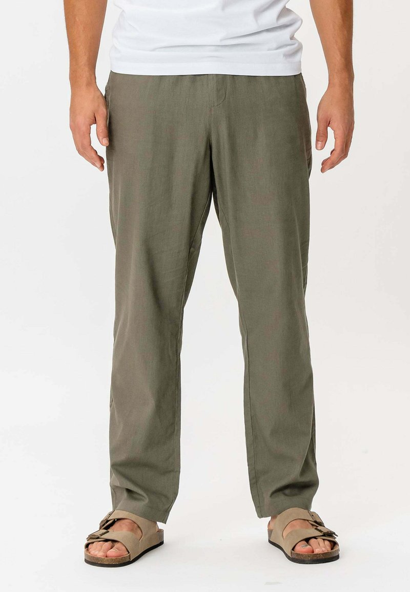 Letvægts olivengrønne bukser med en løs pasform, stofblanding af bomuld og et design med lige ben. Sammen med brune sandaler.
