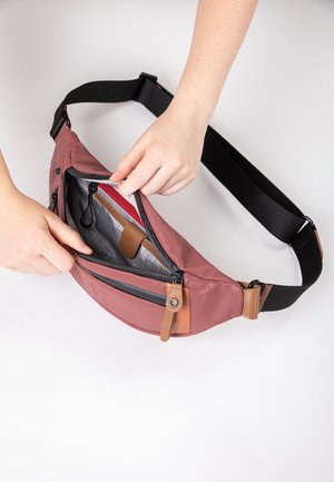 Kompakte pinke Gürteltasche mit texturiertem Äußeren, Reißverschlussfächern und braunen Lederakzenten. Verstellbarer schwarzer Riemen für sicheren Tragekomfort.