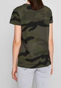 Kraťasové tričko v tmavě zelené a černé barvě, krátké rukávy, kulatý výstřih, jemný materiál, s kamuflážním vzorem na zádech.