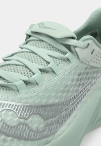 Light green athletic shoe with mesh upper, textured accents, and silver detailing. Features a padded tongue and flat laces.