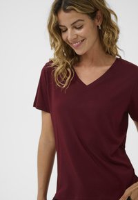 Burgundy V-neck t-shirt with short sleeves, made from soft fabric, featuring a relaxed fit and smooth texture. Accents include minimal stitching.