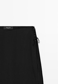 Sort nederdel med knaplukning i siden og bindedetalje, lige snit, lavet af Massimo Dutti.