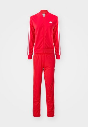 Röd träningsdräkt med en zip-up jacka och byxor med elastisk midja. Har vita dekorativa ränder och logotyp på bröstet och låret.