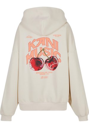 Kremowa bluza z kapturem z graficznym nadrukiem dwóch wiśni oraz napisem "KANI MUSIC" w wyraźnej pomarańczowej czcionce, z kieszenią kangurką i ściągaczami na rękawach.