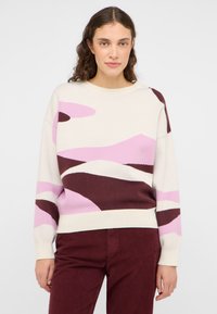 Gehaakte trui met een crèmekleurige basis en abstracte patronen in roze, bruin en bordeaux. Ronde halslijn en ribgebreide manchetten. Zachte textuur.