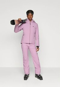 Ski-outfit, bestaande uit een lichtpaarse jas en bijpassende broek. Voorzien van een zwart logo en skibril. Houdt een snowboard vast met zwarte binding.