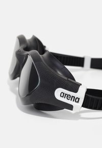 Crne plivačke naočale s teksturiranim okvirom, sivo stakla i bijelim logotipom. Podesivi remen za sigurno pristajanje.