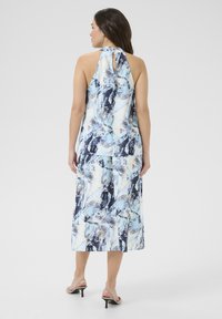Halternek jurk in een abstract patroon van blauw, zwart en crème. Vloeiende stof met een jurk van middellange lengte en een subtiele sleutelgatdetail aan de achterkant.