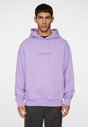 Lilla hoodie med en frontlomme, snorhue og broderet logo. Lange ærmer og ribstrikkede manchetter fuldender det afslappede design.
