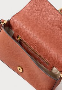 Borsa in pelle di un caldo colore terracotta con una finitura texturizzata. Presenta una tasca interna con zip e dettagli in metallo dorato.