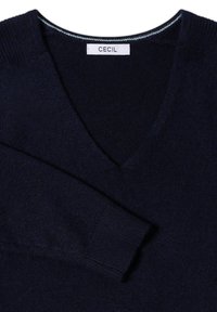 Dunkelblaues V-Ausschnitt-Pullover aus weichem Stoff, mit gerippten Bündchen und einem kontrastierenden inneren Kragenbesatz. Das Etikett trägt die Aufschrift "CECIL."