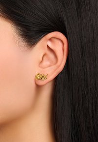Gold-tone stud earring shaped like a rose with detailed leaves, textured surface, and a secure backing, worn in the ear.