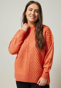 Oranger Strickpullover mit hohem Kragen, ausgestattet mit geripptem Textur und diagonalen Mustern. Lange Ärmel und eine lockere Passform.