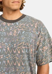Camiseta gris de manga corta con escote redondo, que presenta patrones abstractos en azul claro y melocotón. Tela suave con un corte holgado.