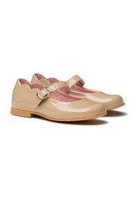 Zapatos Mary Jane de charol beige con bordes ondulados, interior rosa y hebilla lateral; suela plana con una suela exterior marrón claro.