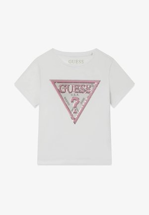 Bela bombažna majica s kratkimi rokavi, ki ima rožnato trikotno obliko iz bleščic in napis "GUESS" v kovinskih črkah.
