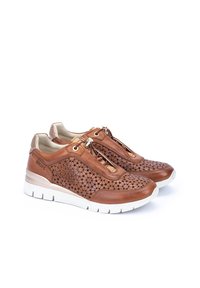 Zapatillas de cuero marrón con recortes florales, con cierre de cremallera y suela de goma blanca. Parte superior texturizada con detalles en tono dorado.