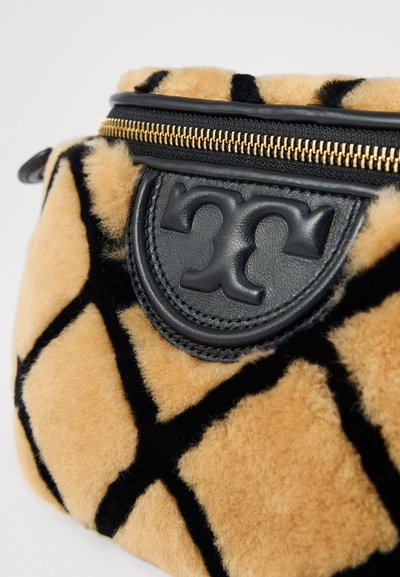 Sac à motif carreaux tan et noir avec une texture en peluche, doté d'un patch en cuir noir et de détails en métal doré sur la fermeture éclair.