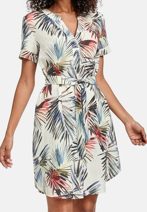 Robe ceinturée à manches courtes avec imprimé de feuilles tropicales colorées en rouge, bleu, noir et vert sur un tissu léger, portée par une personne debout.