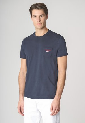 Maglietta in cotone blu navy con scollo rotondo e maniche corte. Presenta una tasca sul petto con testo rosso e un dettaglio del logo ricamato.