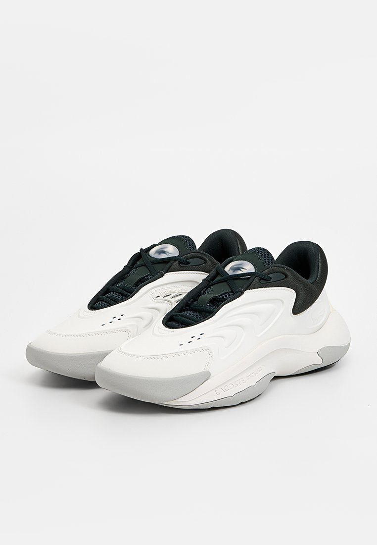 White and black athletic shoes with a textured upper, rounded shape, contrasting laces, and cushioning sole. Notable logo on the side.