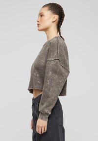 Grå kort sweatshirt med tekstur og falmet finish samt drop shoulder-design. Lange ermer med ribbede mansjetter og rå kantdetaljer.