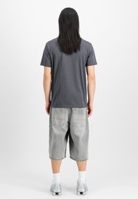 Kolgrå t-shirt med korta ärmar, i kombination med ljusgrå denimshorts. Noterbara egenskaper inkluderar bakfickor och en avslappnad passform.