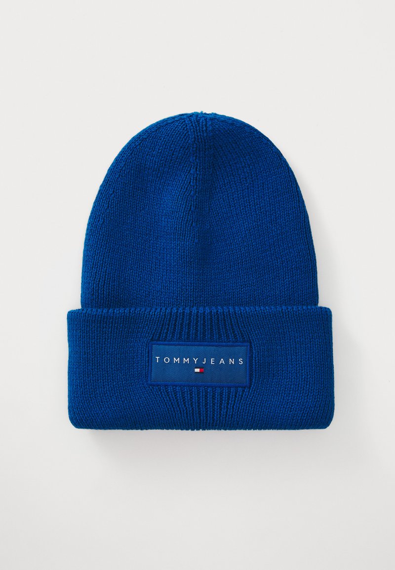 Căciulă tricotată albastră cu mansetă pliată. Prezintă un eticheta țesută rectangulară cu "TOMMY JEANS" și accentele logo-ului. Material texturat.