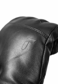 Black leather glove featuring a textured surface and a stitched seam, with a small, embossed logo accent on one side.