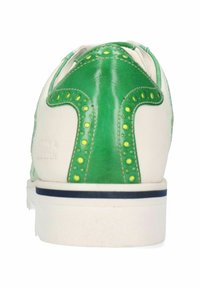 Sneaker bianco con dettagli in pelle verde, caratterizzato da un design distintivo a forma di verde con borchie gialle e una suola a strisce blu.