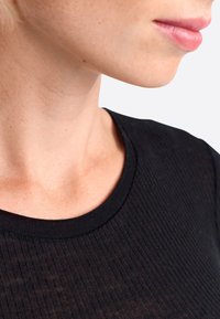 Schwarzes geripptes Strickoberteil mit rundem Ausschnitt, das die Textur und die enge Passform im Hals- und Schulterbereich betont.