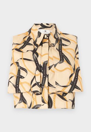 Beige ermeløs bluse med svart bånd og gullkjedeprint, med spiss krage og folder foran.