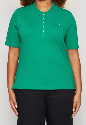 Grünes Poloshirt mit Kragen, kurzen Ärmeln und Knopfleiste. Mit einem kleinen Logo auf der Brust. Der Stoff wirkt glatt und leicht.