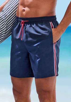 Costume da bagno blu con cintura elastica e coulisse rossa, caratterizzato da strisce laterali bianche e rosse. Tessuto liscio, design a lunghezza ginocchio.