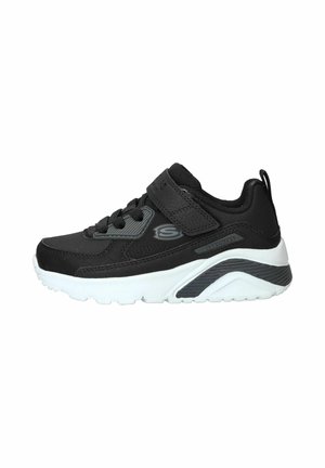 Baskets Skechers noires et grises avec semelle blanche, lacets à l'avant et bride Velcro réglable, vues de côté sur fond blanc.
