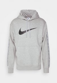 Grå hoodie med en stor svart Nike swoosh-logotyp. Har en justerbar huva, framficka och randiga detaljer längs ärmarna.