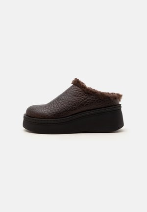 Mørkebrunt tekstureret slip-on træsko med tyk sort sål og blød pelsforing rundt om åbningen for ekstra komfort og varme.