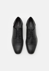 Chaussures de ville en cuir noir avec une finition lisse, un bout rond et des lacets fins ; comprenant des détails cousus et un design minimaliste.