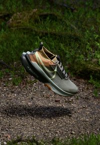 Baskets de course Nike ZoomX en vert olive et tan. Comprend un dessus perforé, des lacets plats et une semelle rembourrée avec des accents orange.