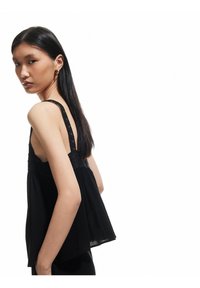 Top nero senza maniche con dettagli in pizzo, dalla forma fluida, con dettagli testurizzati e una vestibilità rilassata, che mostra una leggera drappeggiatura sul retro.