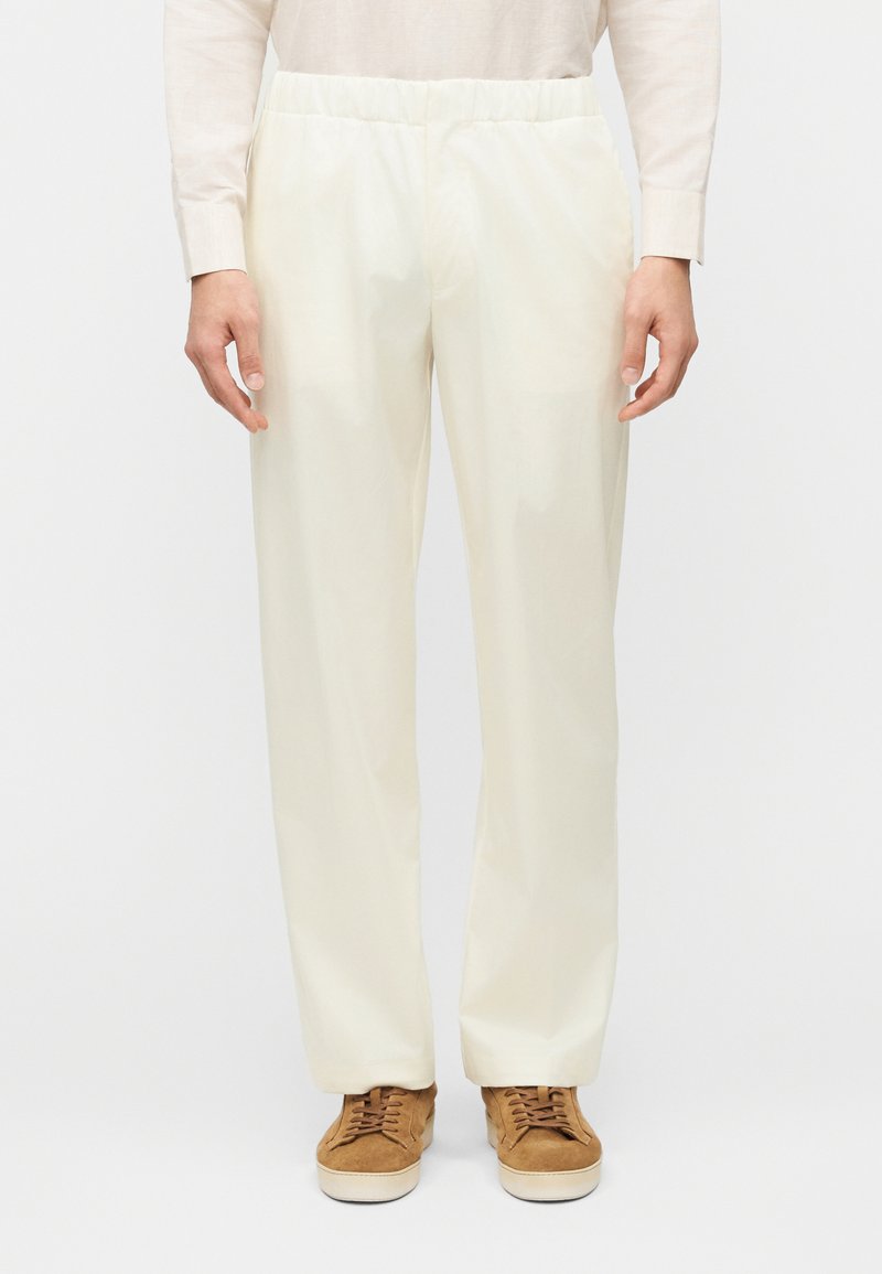 Κρεμ παντελόνια χαλαρής εφαρμογής με ελαστική μέση. Κατασκευασμένα από απαλό ύφασμα, διαθέτουν ίσια πόδια και χωρίς ορατά μοτίβα.