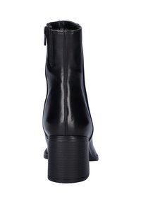 Zwarte leren enkelboot met blokhak en zijrits, bekeken vanaf de achterkant op een witte achtergrond.