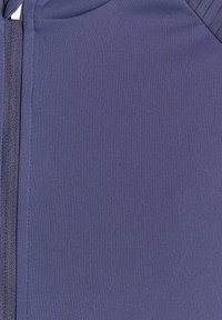Gros plan sur un tissu bleu avec une fermeture éclair verticale et des coutures détaillées le long des bords.