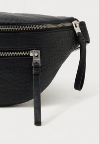 Pochete de couro preta com superfície texturizada, fechos de zíper prateados e alça ajustável. Apresenta um bolso frontal com fecho de zíper.